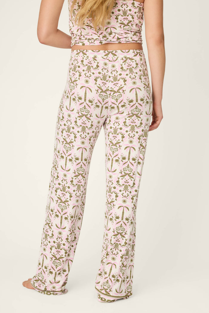 A person with long blonde hair, seen from the back, wears P.J. Salvage Déjà Vu Dreams Tiki Time Open Leg Pants—a relaxed, comfortable floral and palm tree print outfit with a matching sleeveless top.