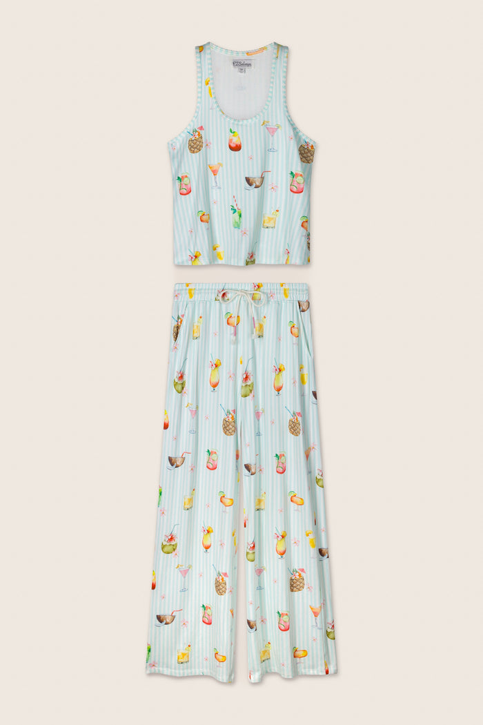 The P.J. Salvage "It's Five O'clock Somewhere" Cocktail Print Long PJ Set features a sleeveless, cropped tank top and wide-leg pants with thin blue and white stripes and a vibrant fruit and drink motif, displayed flat on a neutral background.