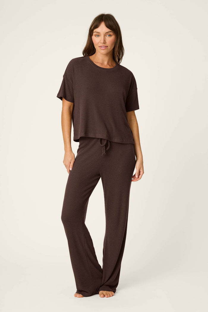 A woman stands barefoot against a plain background, wearing the P.J. Salvage Textured Essentials Chocolate Brown Short Sleeve Top and matching wide-leg pants.
